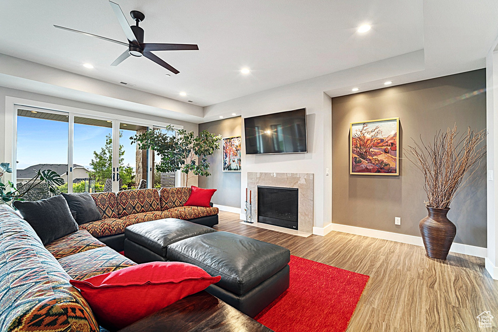 Living room featuring wood finished floors, recessed lighting, baseboards, a premium fireplace, and a ceiling fan
