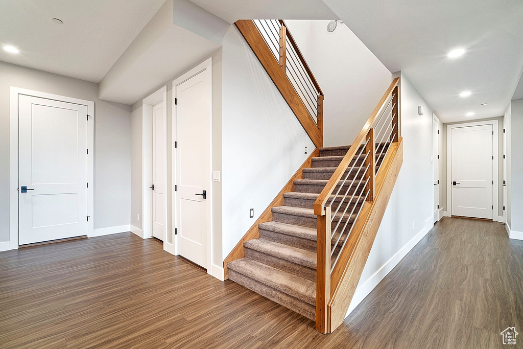 Staircase with wood finished floors, recessed lighting, and baseboards