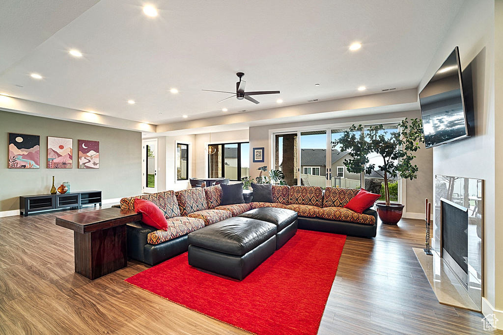 Living area featuring wood finished floors, baseboards, recessed lighting, a ceiling fan, and a premium fireplace