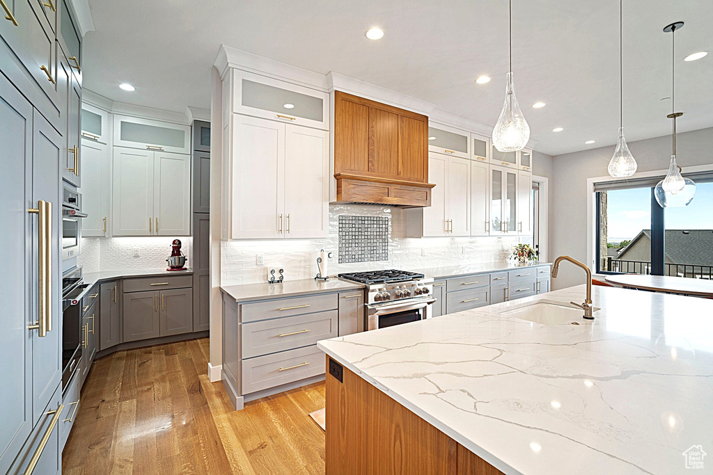 Kitchen featuring a sink, stainless steel appliances, custom exhaust hood, light wood finished floors, and recessed lighting
