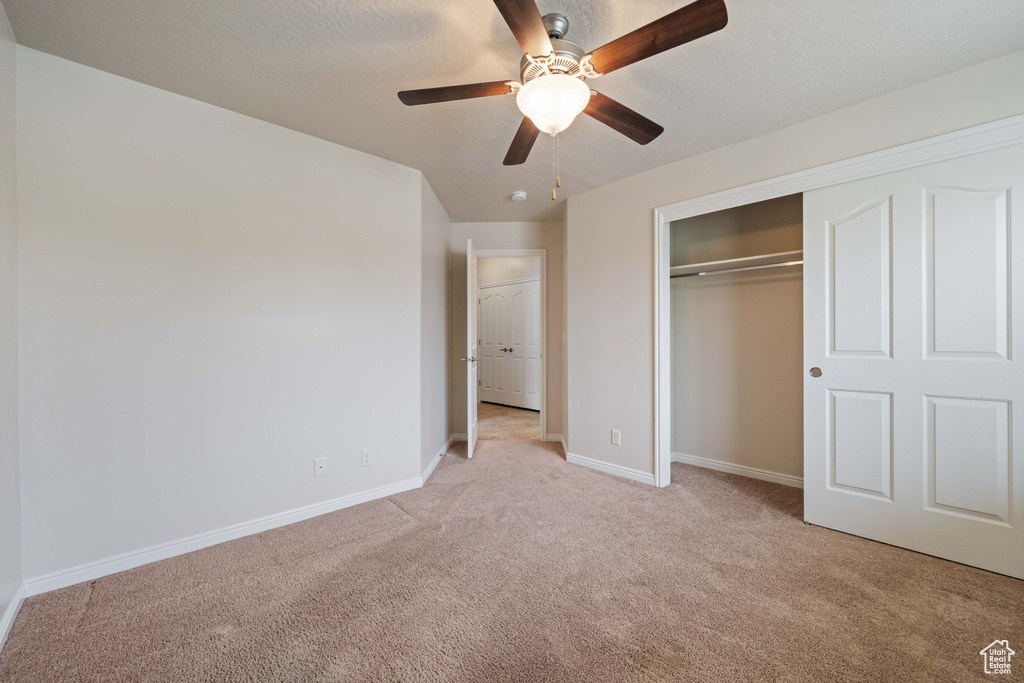 Unfurnished bedroom featuring light carpet, baseboards, a closet, and a ceiling fan