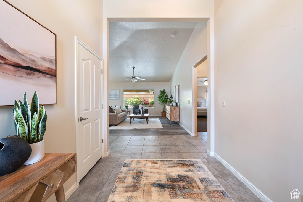 Hall featuring light tile patterned floors, baseboards, and lofted ceiling