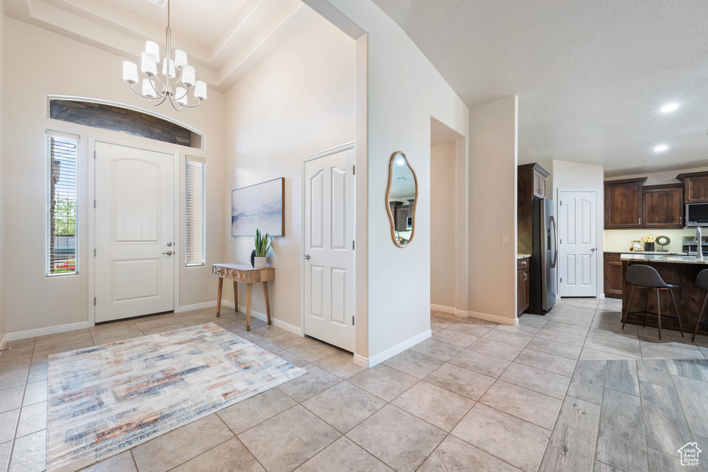 Foyer entrance with a chandelier, recessed lighting, light tile patterned floors, and baseboards