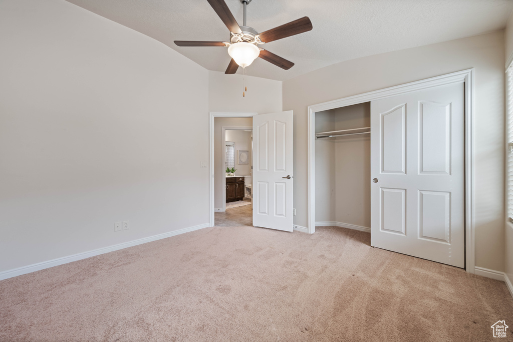 Unfurnished bedroom featuring carpet, vaulted ceiling, baseboards, a closet, and ceiling fan