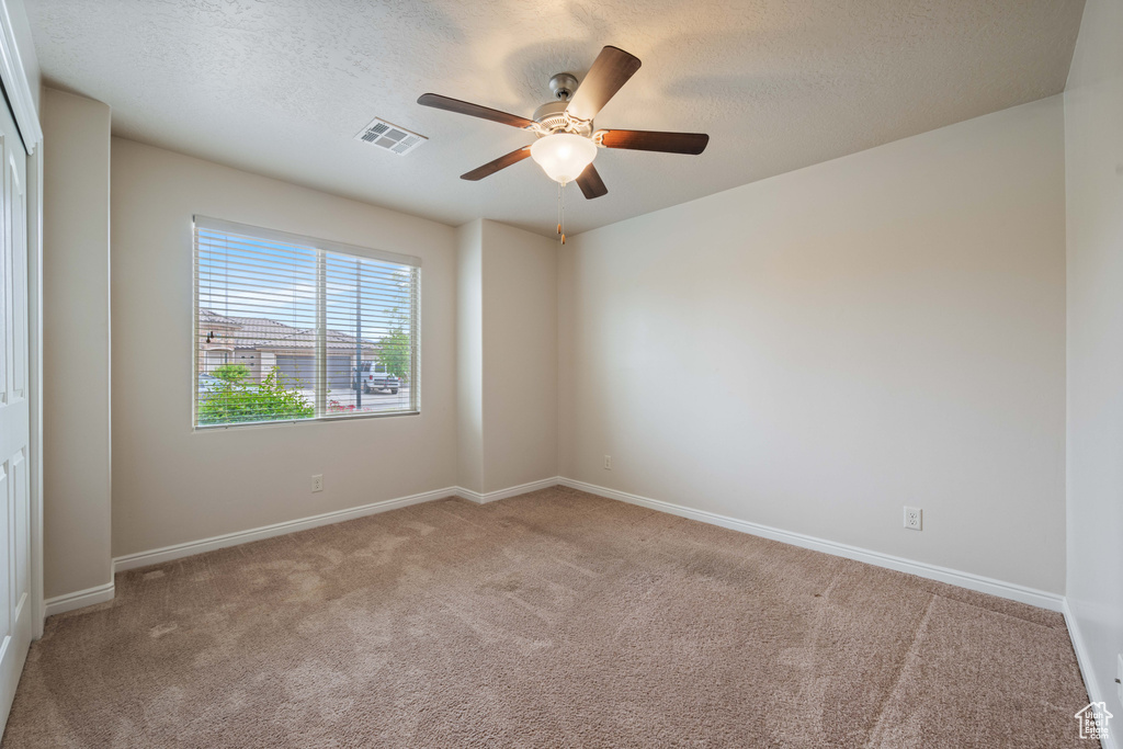 Empty room featuring carpet flooring, a ceiling fan, baseboards, and a textured ceiling