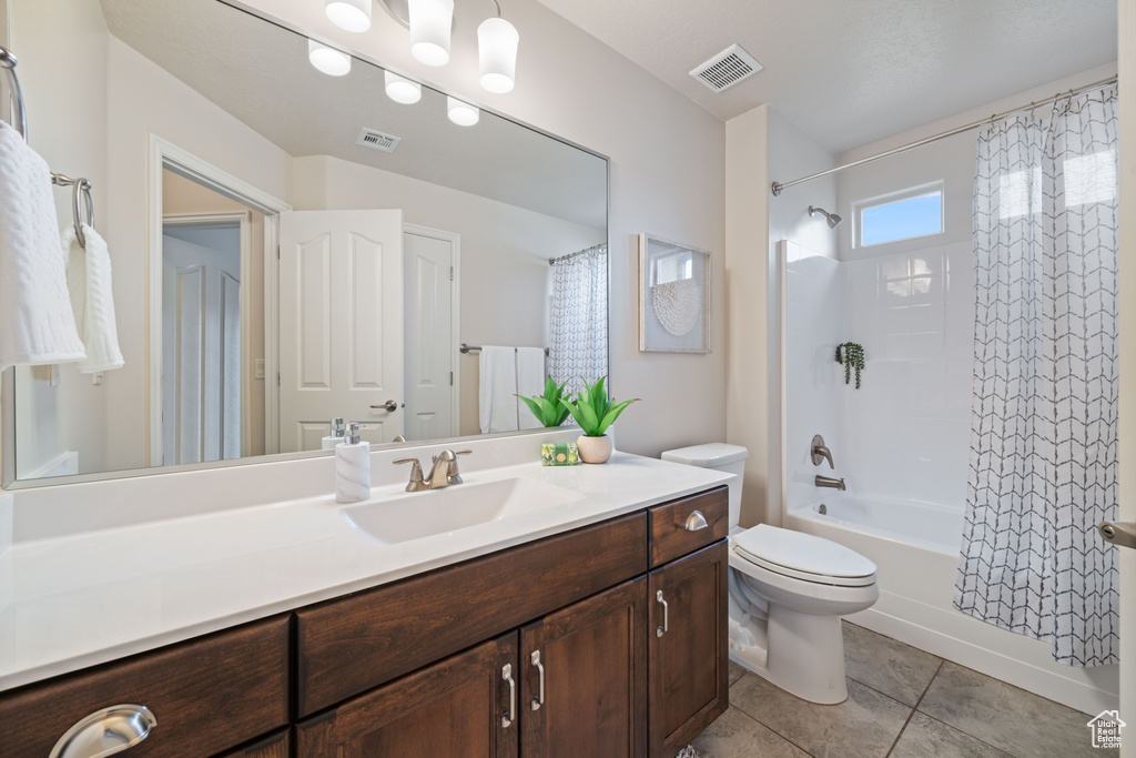 Bathroom with toilet, tile patterned floors, shower / bath combo with shower curtain, and vanity
