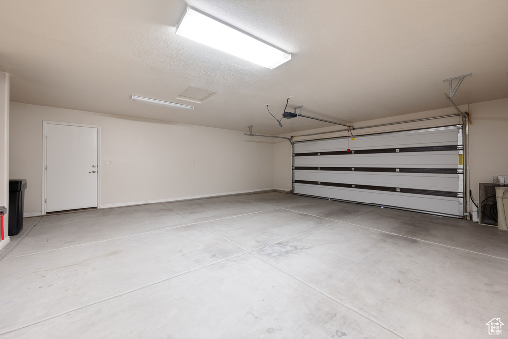 Garage featuring a garage door opener and baseboards