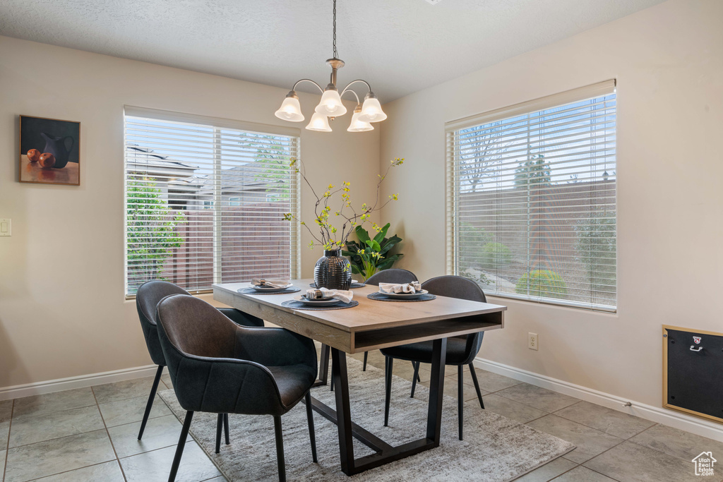 Dining room featuring a chandelier, plenty of natural light, baseboards, and light tile patterned flooring