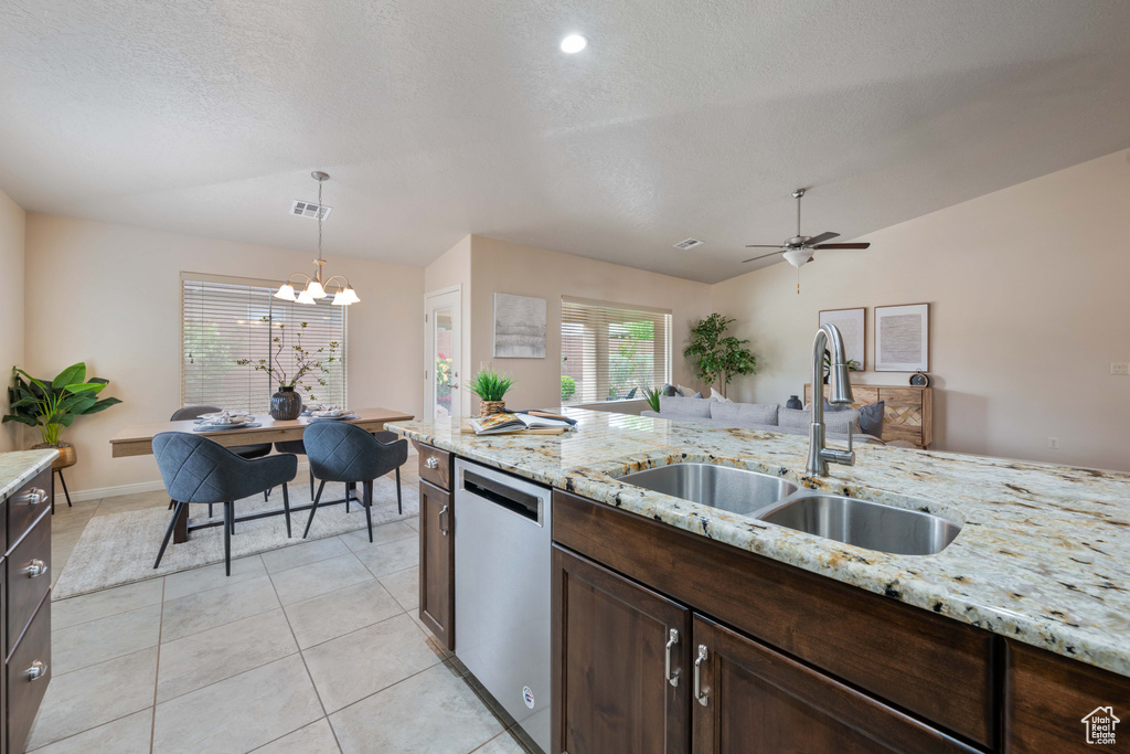 Kitchen featuring stainless steel dishwasher, a sink, a chandelier, dark brown cabinetry, and a textured ceiling