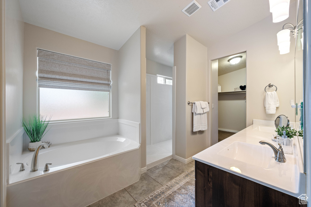 Bathroom with a garden tub, double vanity, tile patterned flooring, walk in shower, and baseboards