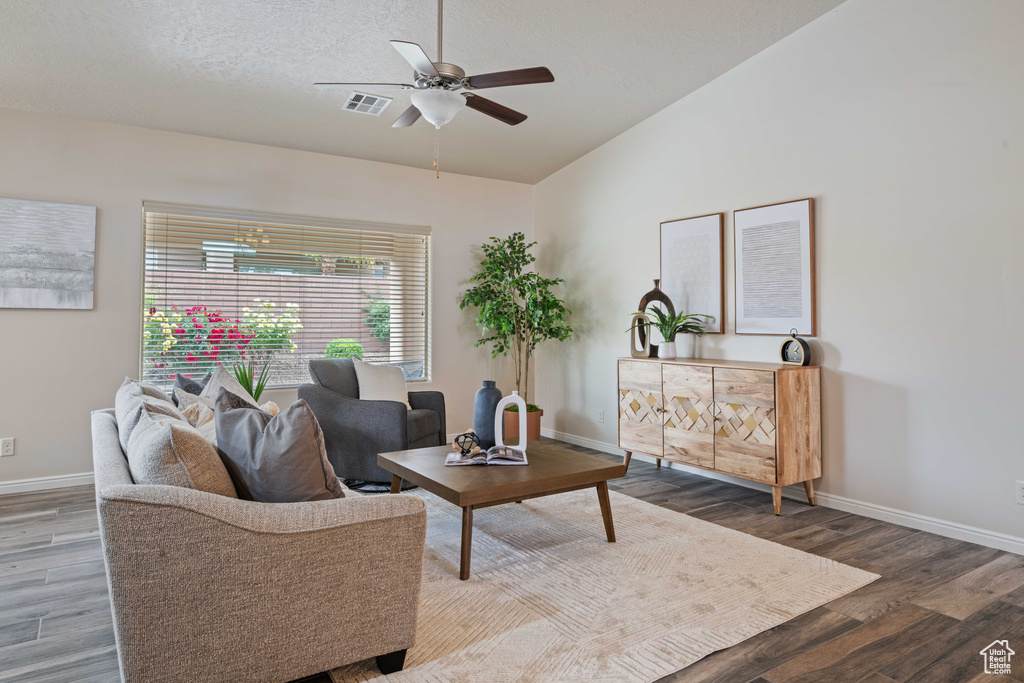 Living room with wood finished floors, a ceiling fan, baseboards, and lofted ceiling