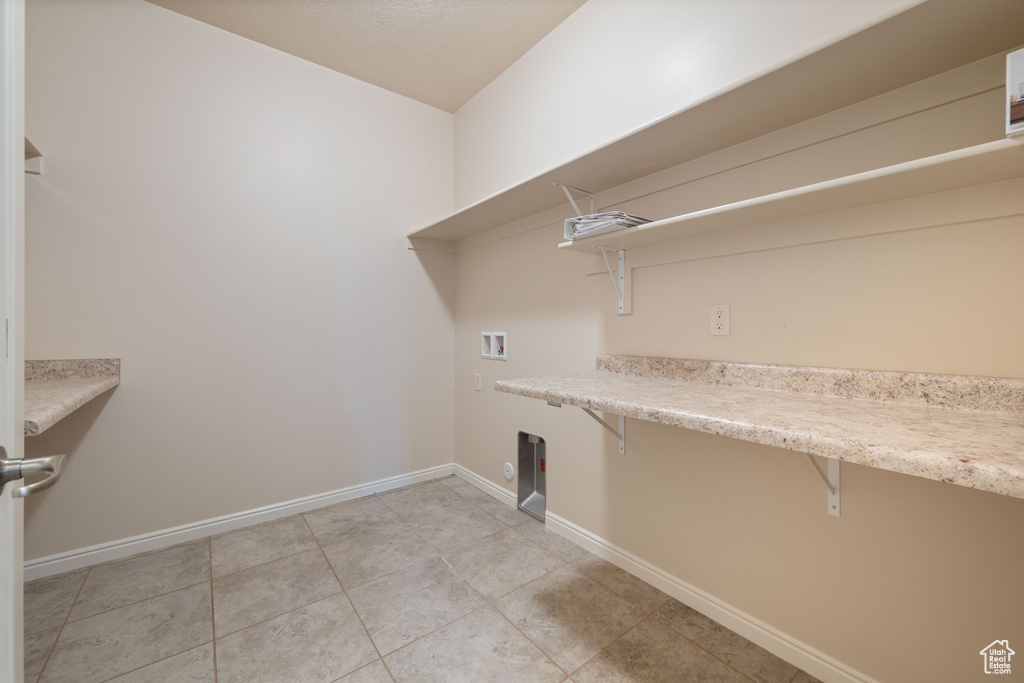 Laundry room with washer hookup, baseboards, light tile patterned flooring, and electric dryer hookup