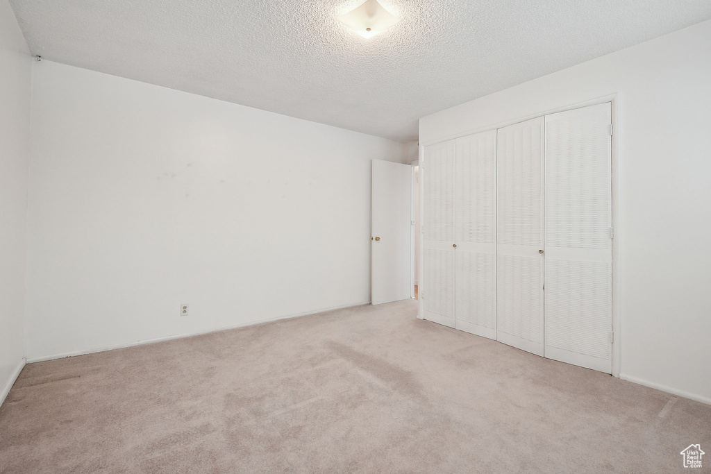 Unfurnished bedroom featuring carpet, a closet, and a textured ceiling