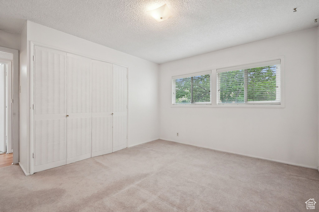 Unfurnished bedroom with carpet flooring, a closet, and a textured ceiling