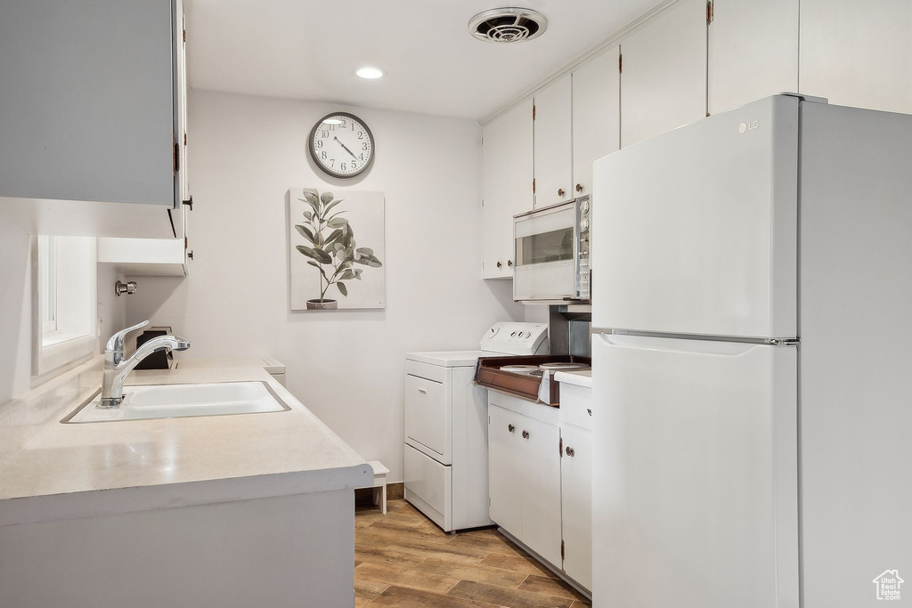 Laundry area with washer and dryer, light wood-style floors, and recessed lighting