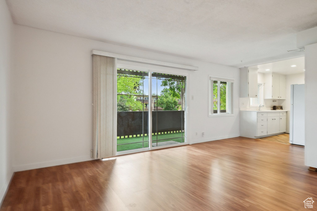 Unfurnished living room featuring a sink, light wood-type flooring, and baseboards