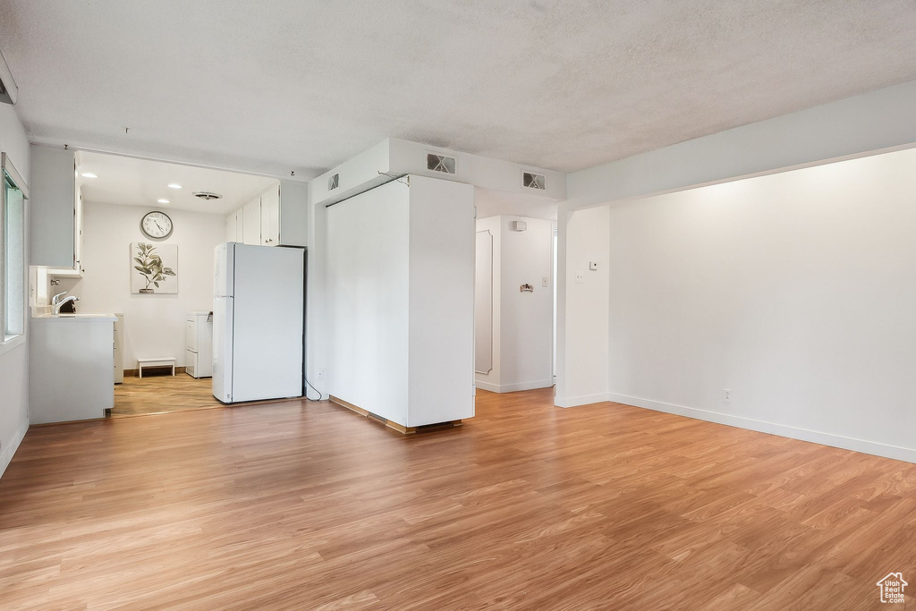 Unfurnished living room with light wood-type flooring, baseboards, and recessed lighting