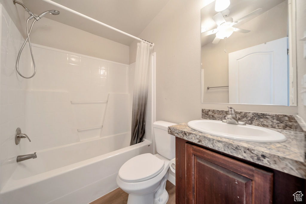 Bathroom featuring vanity, shower / bath combination with curtain, a ceiling fan, and wood finished floors