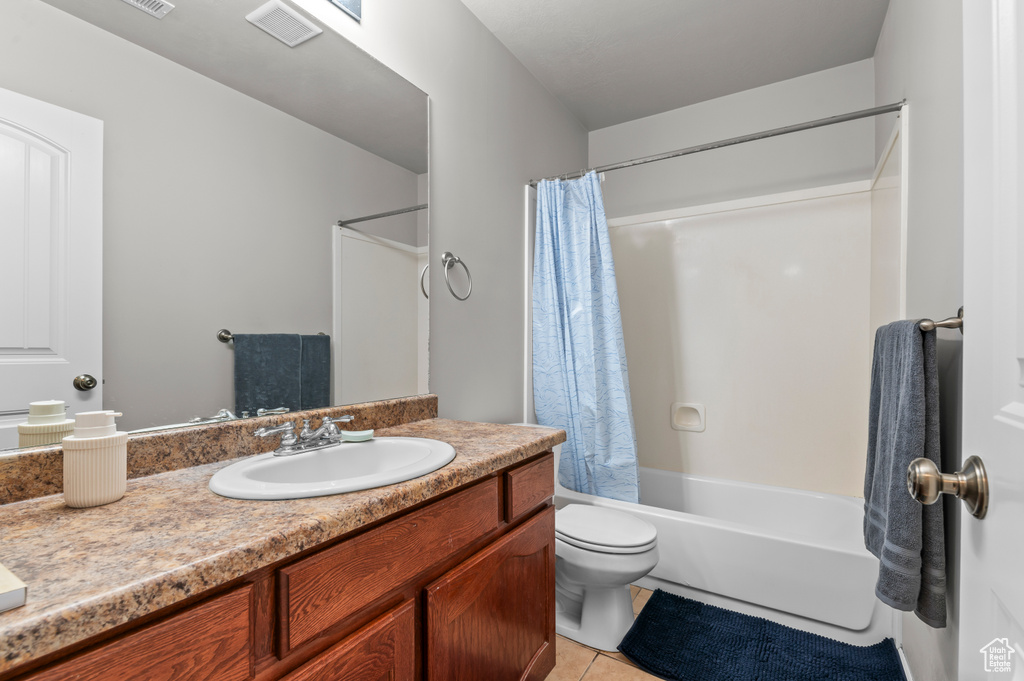 Bathroom featuring toilet, tile patterned floors, vanity, and shower / bathtub combination with curtain