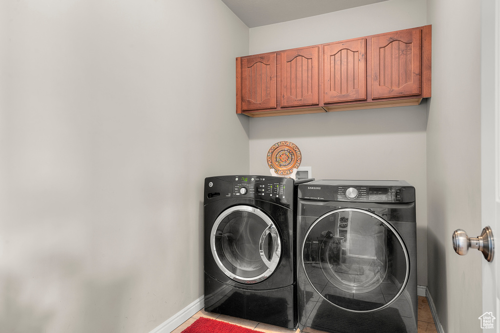 Washroom with washer and clothes dryer, baseboards, cabinet space, and tile patterned flooring
