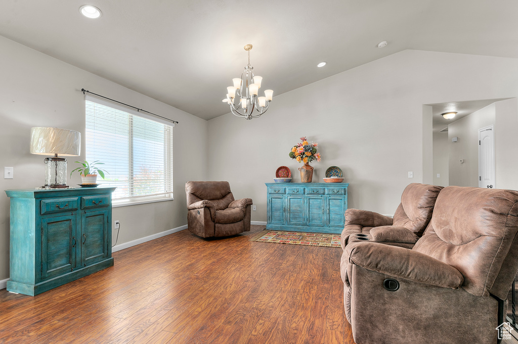 Living room featuring lofted ceiling, dark wood-type flooring, a chandelier, recessed lighting, and baseboards