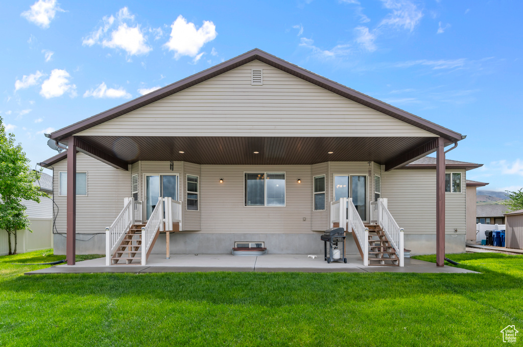 Rear view of property featuring a lawn and a patio area
