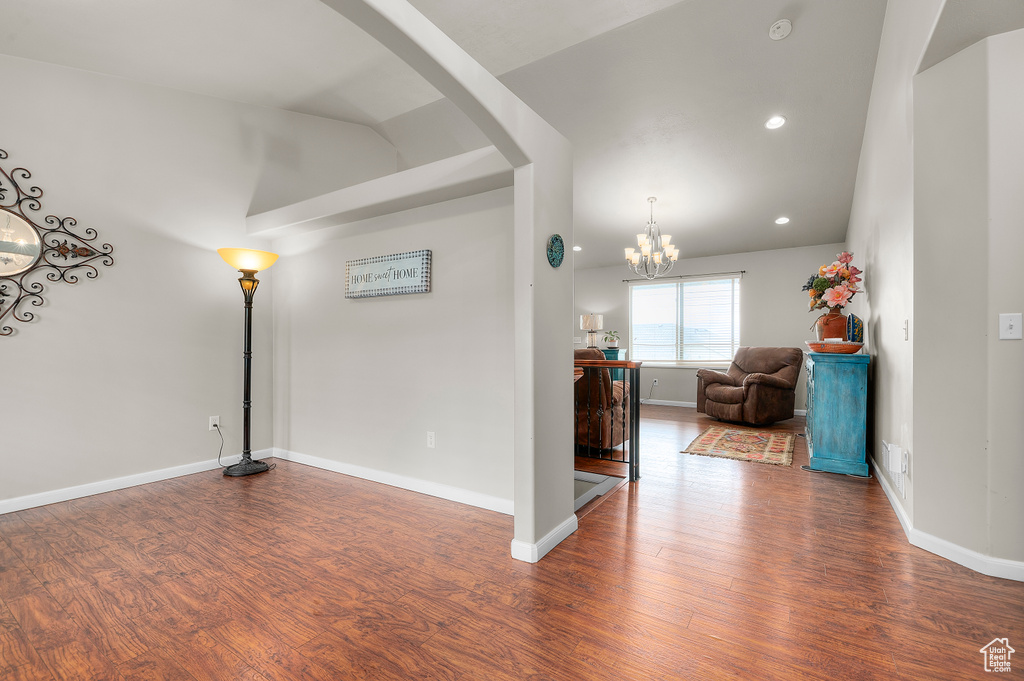 Spare room featuring wood finished floors, arched walkways, recessed lighting, a chandelier, and baseboards