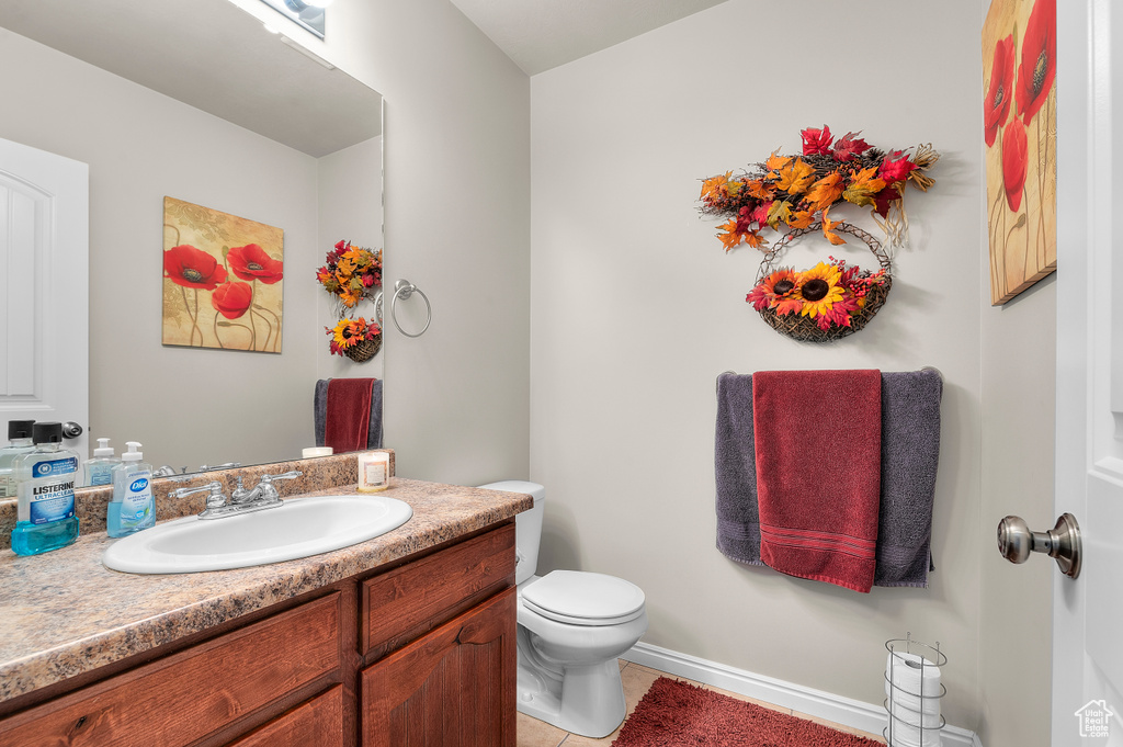 Half bathroom with vanity, toilet, and tile patterned flooring