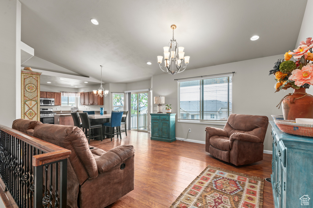 Living room featuring a chandelier, recessed lighting, vaulted ceiling, wood finished floors, and baseboards