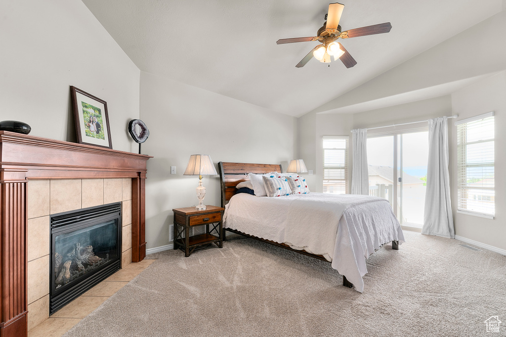 Bedroom with vaulted ceiling, access to exterior, light carpet, a tiled fireplace, and baseboards