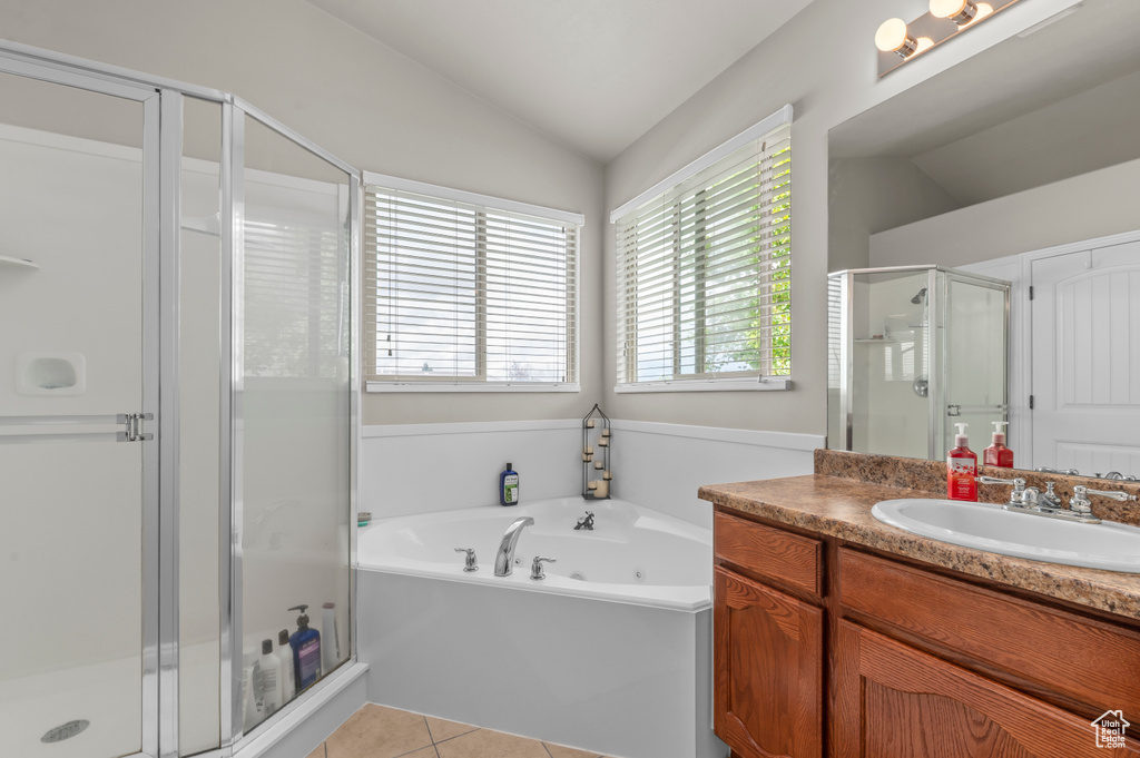 Bathroom with vaulted ceiling, a shower stall, vanity, a jetted tub, and tile patterned flooring
