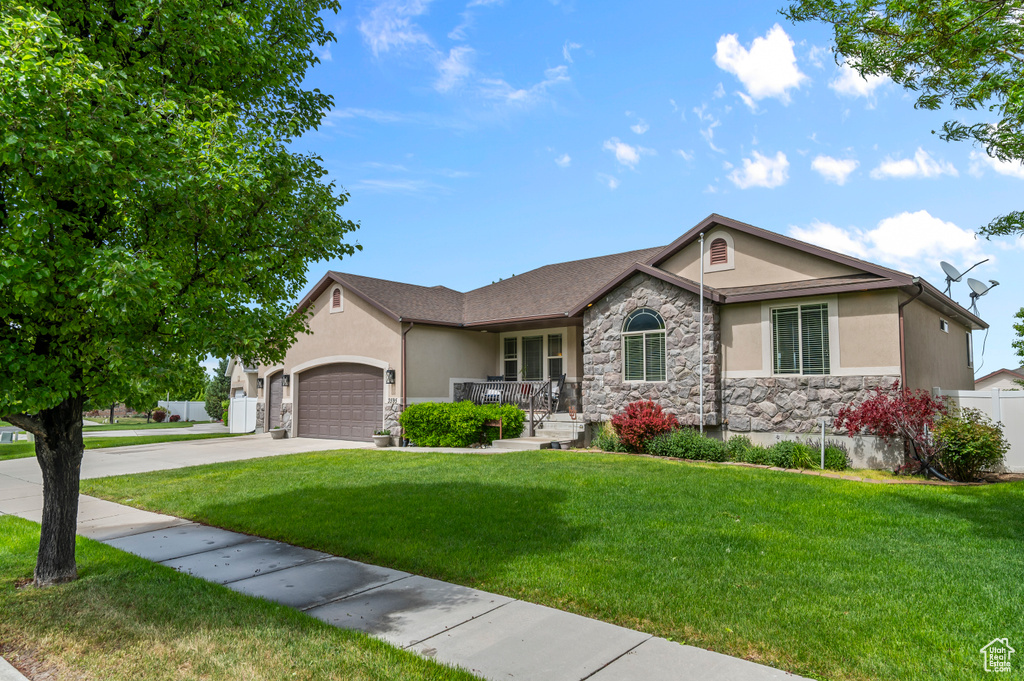 Single story home with stone siding, stucco siding, a garage, and concrete driveway