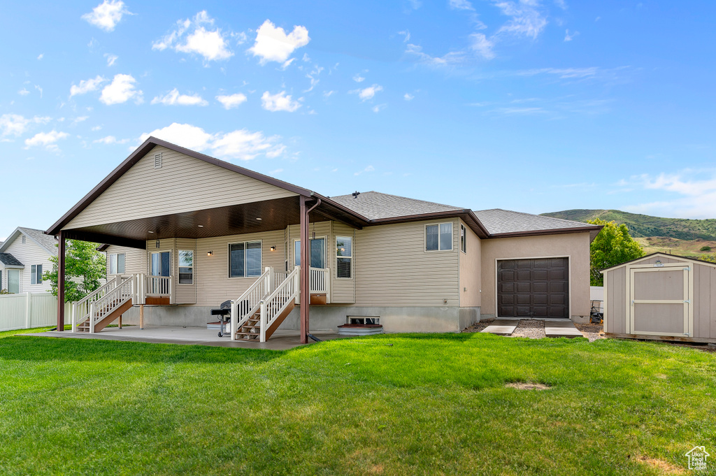 Rear view of property featuring a storage unit, an attached garage, and an outbuilding
