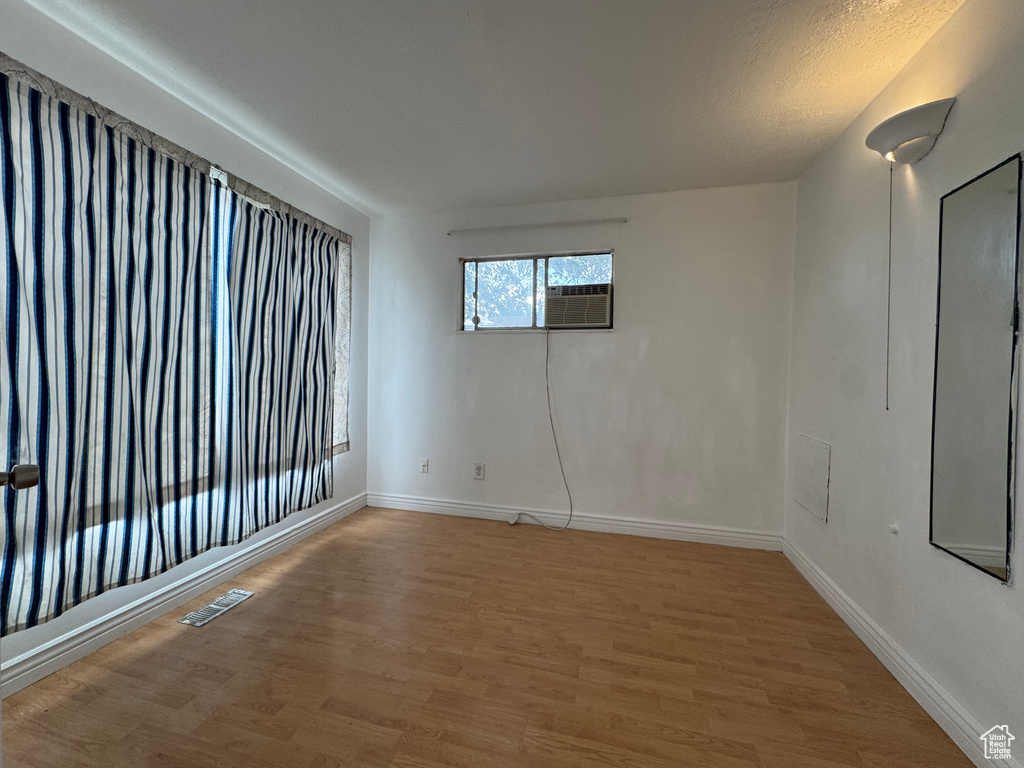 Unfurnished room with light wood-style floors, baseboards, and cooling unit