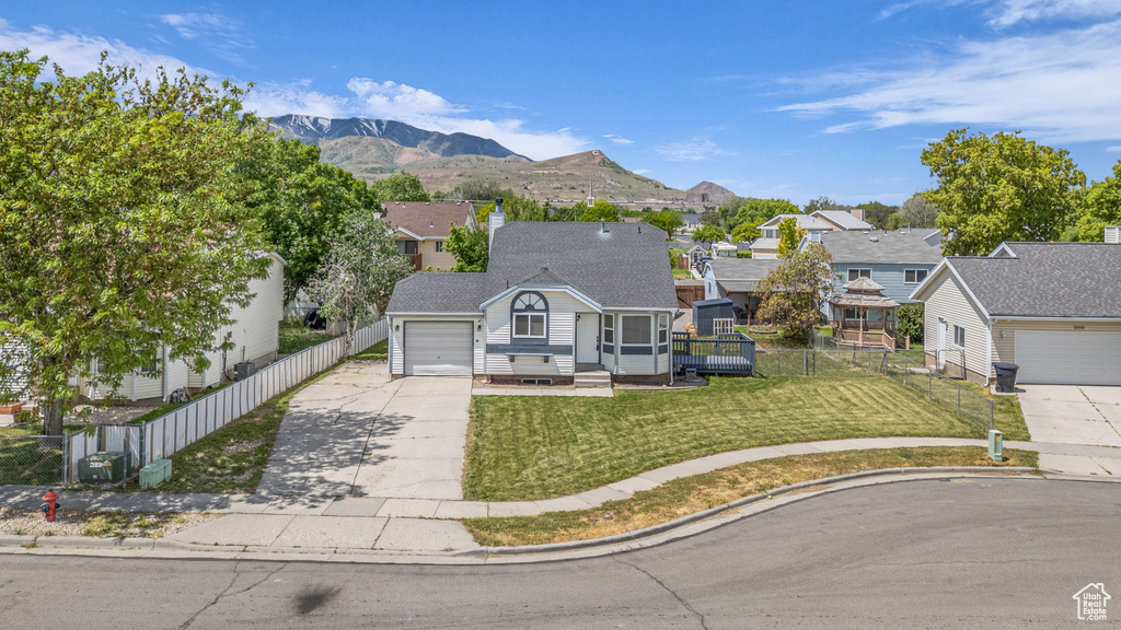 View of front of home featuring driveway, a residential view, an attached garage, and a mountain view