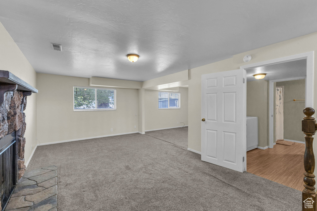 Unfurnished living room featuring a fireplace, washer / clothes dryer, carpet floors, and baseboards