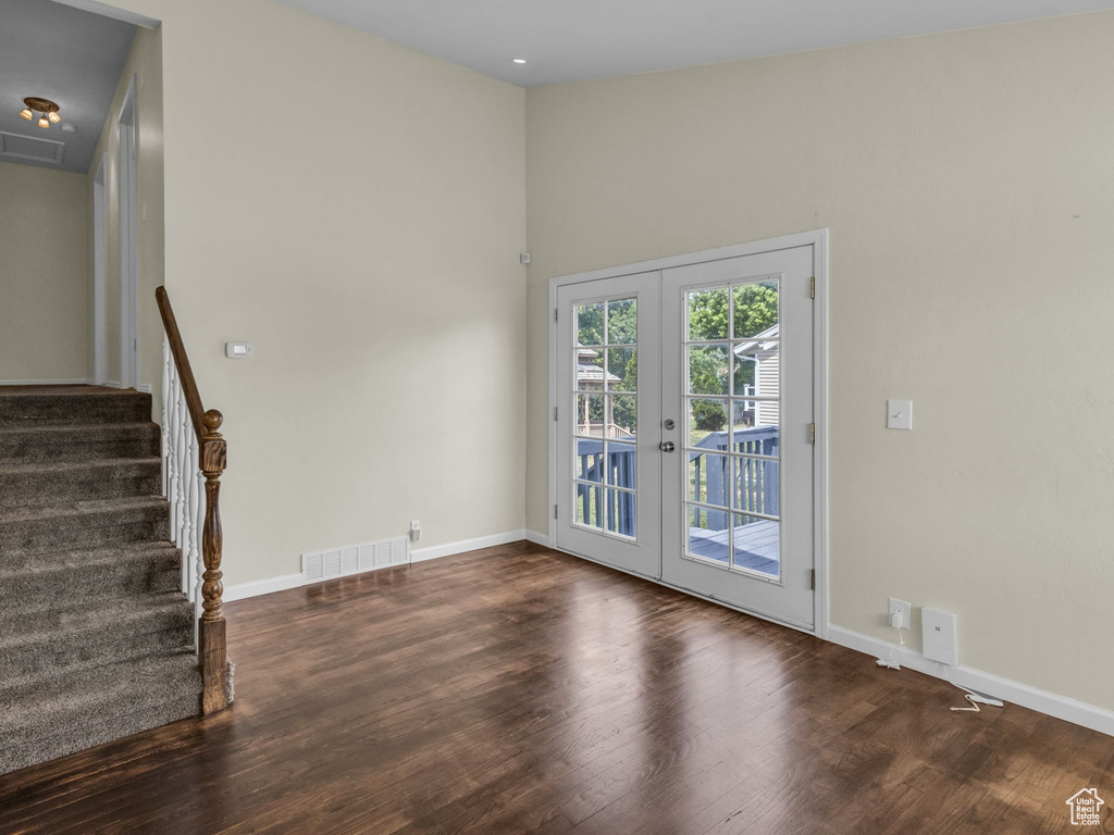 Unfurnished living room featuring french doors, wood finished floors, stairway, and baseboards