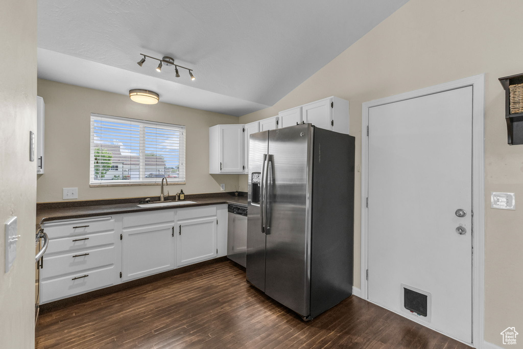 Kitchen featuring stainless steel appliances, a sink, dark countertops, white cabinetry, and dark wood-style flooring