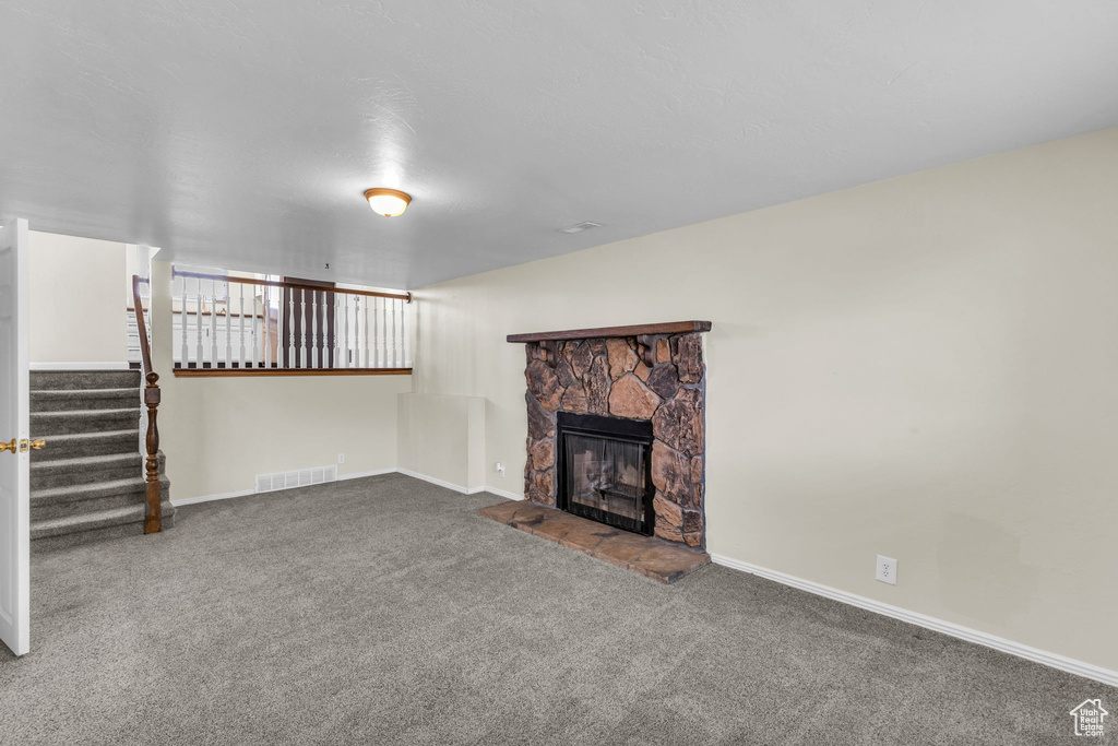 Unfurnished living room with a fireplace, carpet flooring, stairs, and baseboards