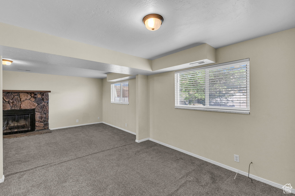 Below grade area with carpet flooring, baseboards, healthy amount of natural light, and a fireplace