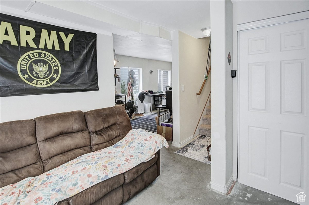Living area with unfinished concrete floors, baseboards, and stairway