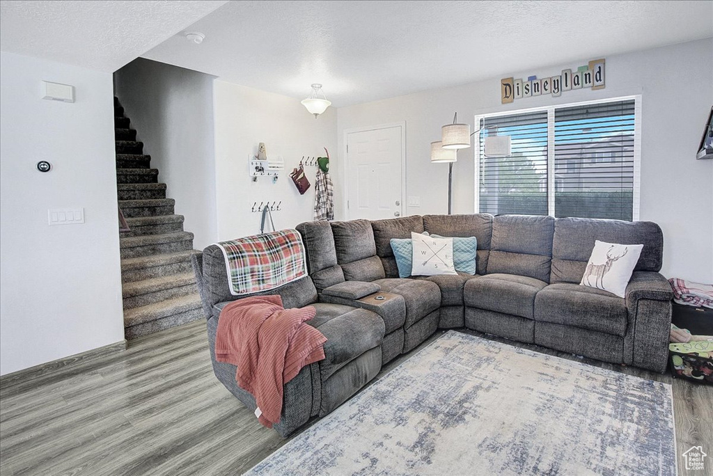 Living room with wood finished floors, stairway, and a textured ceiling