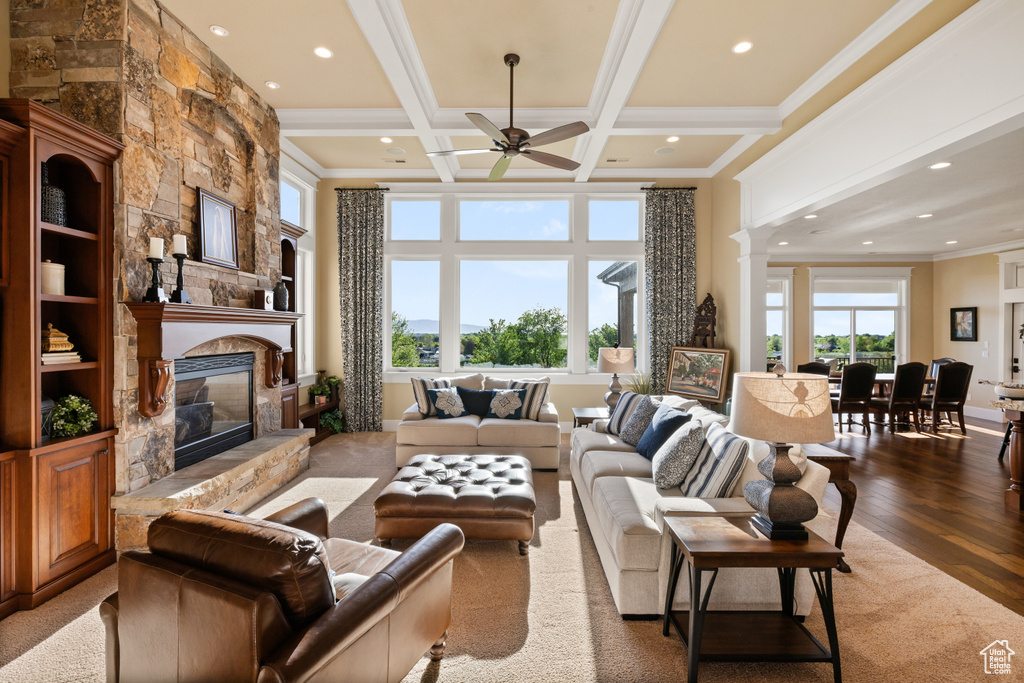 Living area featuring a stone fireplace, recessed lighting, ceiling fan, wood finished floors, and beam ceiling
