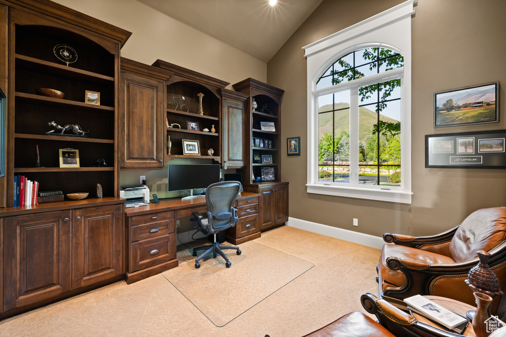 Office area with light carpet, baseboards, vaulted ceiling, and built in desk