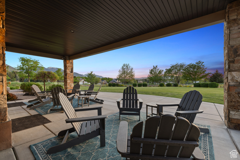 Patio terrace at dusk featuring a yard and a mountain view