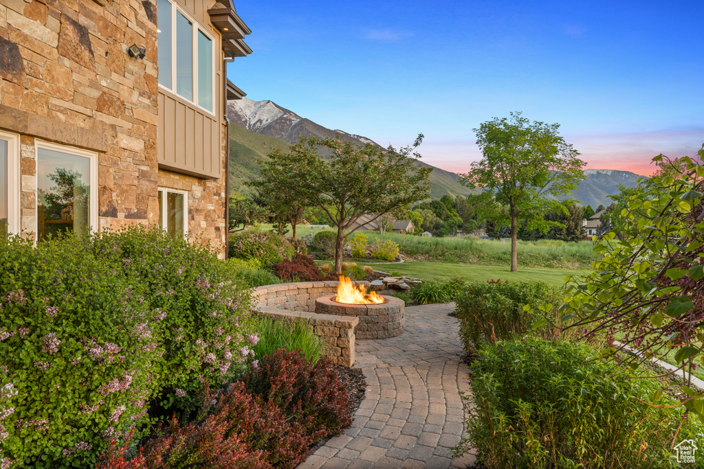 View of green lawn featuring an outdoor fire pit, a mountain view, and a patio area