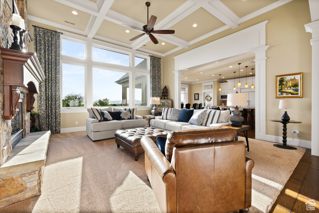 Living area with decorative columns, a ceiling fan, a towering ceiling, a fireplace, and baseboards
