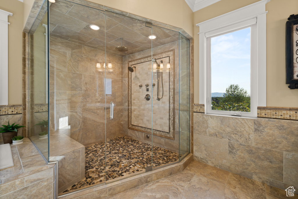 Bathroom with a stall shower, crown molding, and tile walls