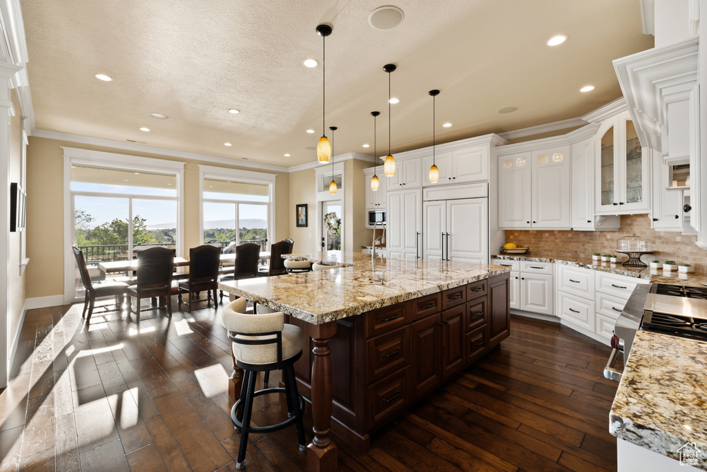 Kitchen featuring crown molding, dark wood-style floors, recessed lighting, tasteful backsplash, and white cabinets