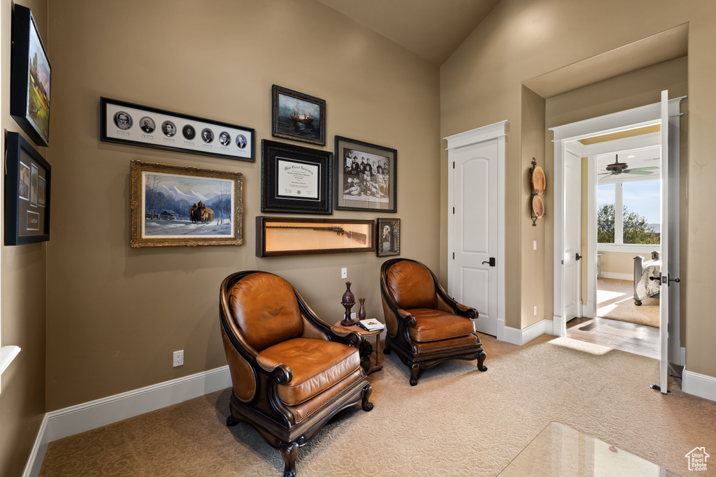 Living area featuring carpet flooring, baseboards, and lofted ceiling